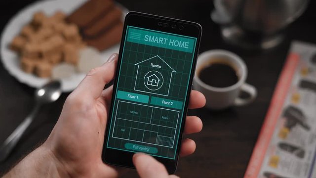Smart home, application on the phone. A man manages various parameters of his home from a smartphone. Smart home technologies allow you to control lighting, temperature, security systems