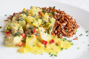 curry with chicken, pine nuts, cilantro, pineapple, chili and bell peppers garnished with red rice