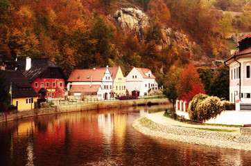 Fototapeta premium Cesky Krumlov - a famous czech historical beautiful town, view to the city river and beautiful autumn street with colorful buildings and fall trees. Travel european background