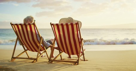 Happy retired couple enjoying beautiful sunset at the beach - Powered by Adobe