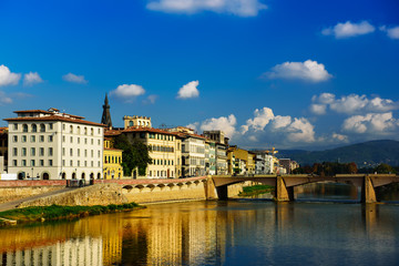 Fototapeta na wymiar Ponte alle Grazie bridge in Florence, Italy with blue sky, clouds and reflection in the river Arno. Travel outdoor sightseeing background.