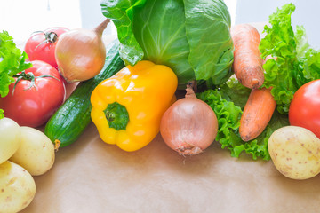 fresh vegetables. Tomatoes, potatoes, cucumber, peppers, onions, lettuce, carrots, cabbage on a table with paper