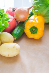 fresh vegetables. Tomatoes, potatoes, cucumber, peppers, onions, lettuce, carrots, cabbage on a table with paper