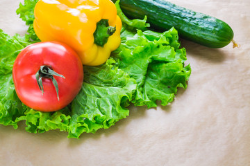 Fresh yellow paprika,cucumber, tomatoes and green salad leaves on a grey background. Space for text.