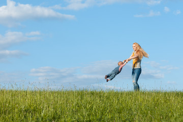 Fototapeta premium Young mother walking with her baby. Mom is circling her child by the hands