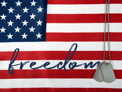 word freedom and military dog tags on American flag