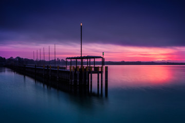 Beautiful sunrise under the deep cloudy sky at the Friedrichshafen harbor.