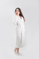 Fototapeta premium Young beautiful brunette with long hair posing standing in a white coat on an isolated background.