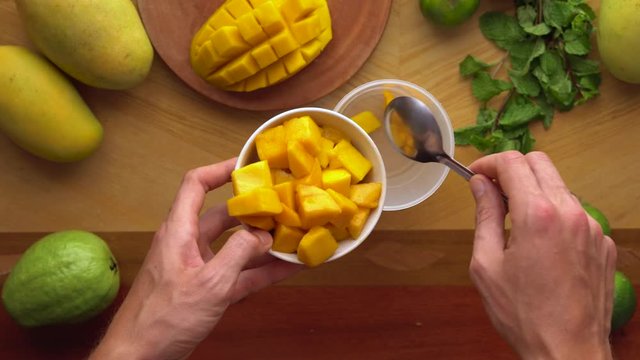 man puts peaces of mango into mixer. Process of making a Juicy mango shake. Healthy life concept