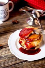 Hearty and tasty breakfast or lunch, fried pancakes with strawberry jam, milk and black tea on a dark wooden background 