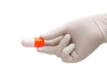 Hand holding a capsule or pill in medical gloves