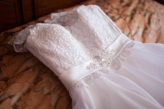 White lace wedding dress on the bed. Day