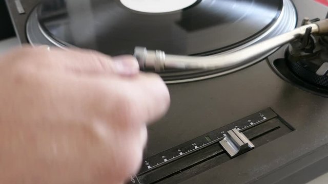 A person puts a spherical needle on a rotating vinyl...