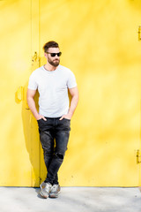 Colorful portrait of a handsome man dressed in white t-shirt and jeans on the yellow background