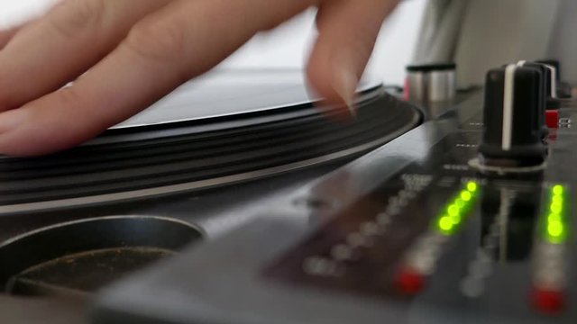 Close up footage of a rotating vinyl and audio levels indicator, a DJ is scratching on the vinyl...
