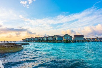 Beautiful sunrise with  water villas  in tropical Maldives island .