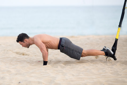 Athletischer Mann macht Beine TRX Training am Strand