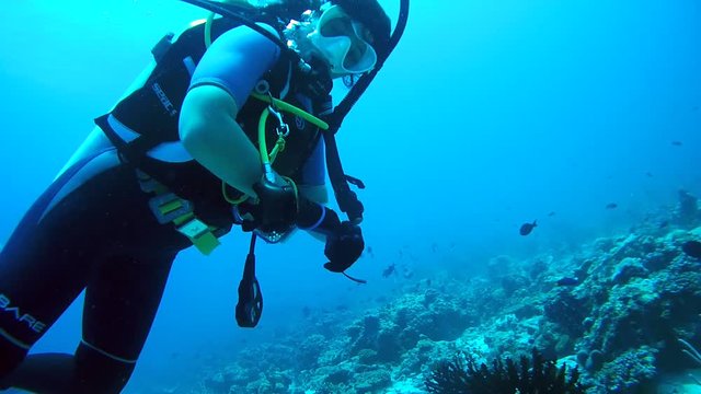 The female scuba diver actively gesticulates and photographs under water, Indian Ocean, Maldives
