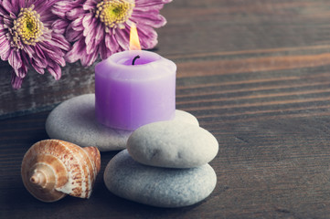 Pebbles, purple lit candle, flowers, shells