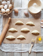 Fototapeta na wymiar Dough preparation recipe homemade croissants or buns ingridients, food flat lay on kitchen table background. Working with flour, eggs, rolling pin or bakery cooking. Text space. Top view.