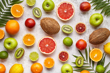 Organic fruit food background. Different citrus fruit, apple, kiwi and coconut on light background. Antioxidant, detox, dieting, clean eating, vegetarian vegan, healthy eating concept. Top view