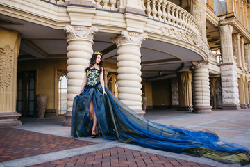 Beautiful woman in a luxurious blue dress with a long train