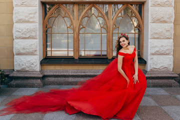 Beautiful woman in a luxurious red dress with a long train