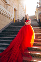 Beautiful woman in a luxurious red dress with a long train