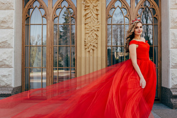 Beautiful woman in a luxurious red dress with a long train