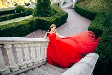 Beautiful woman in a luxurious red dress with a long train