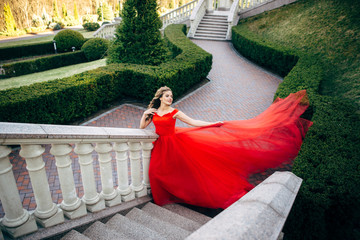 Beautiful woman in a luxurious red dress with a long train