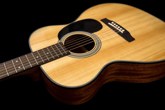 Yellow acoustic wooden guitar on a black background