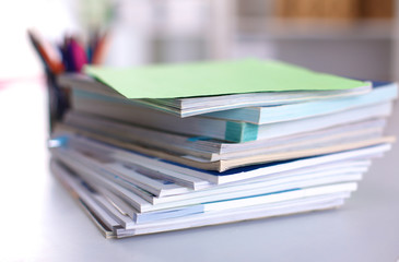 A stack of documentation is on the desktop in the office