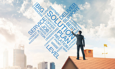 Young businessman standing on house roof and writing leadership 