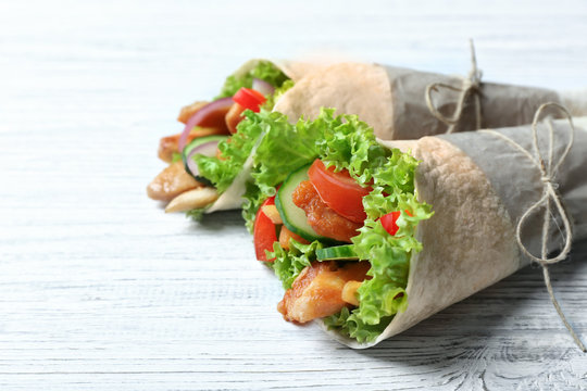 Tasty kebab rolls on white wooden background