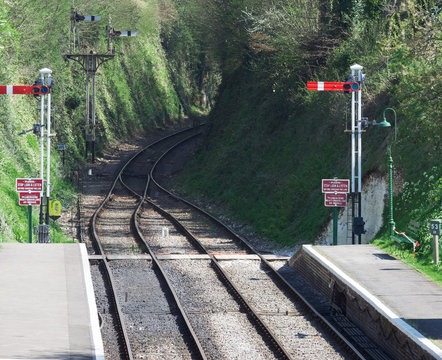 Tracks on a heritage railway line in the UK. Semaphore signals are displayed and the line is double tracked at the station with two platforms.