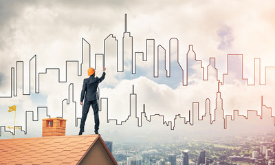 Man architect draw silhouette of modern city on blue sky. Mixed 