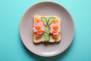 Plate with funny sandwich on color background