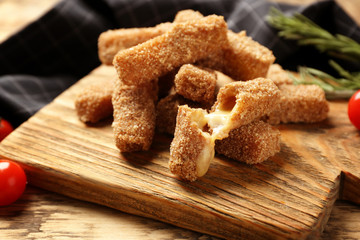 Tasty cheese sticks on cutting board, closeup