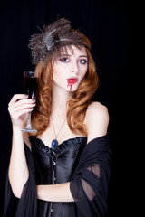 photo of beautiful young woman in vampire character with glass of wine