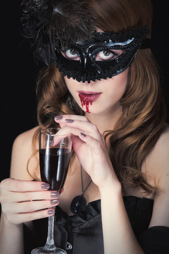 photo of beautiful young woman in vampire character with glass of wine