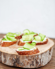 Snacks with cheese feta and cucumber on a wooden board. The concept of food and vegetarianism.