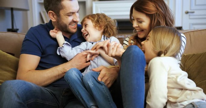 . Happy family spending time together at home. Happy young family sitting on the sofa Mother, father, son, daughter. Beautiful family laughing
