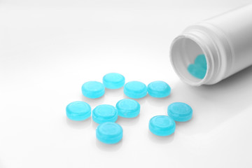 Cough drops spilling out of bottle on white background