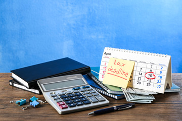Paper sheet with text TAX DEADLINE, calculator and notebooks on wooden table