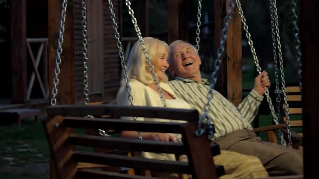 Man and woman, porch swing. Senior couple smiling outdoor.