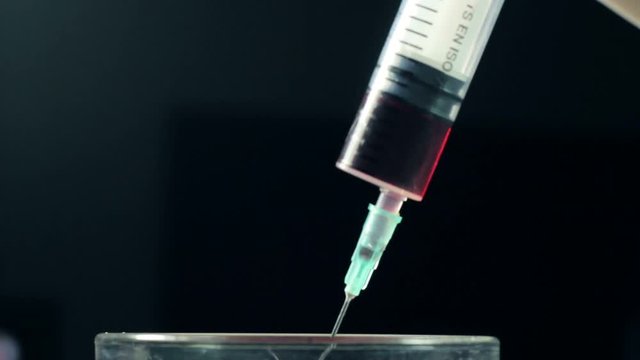 Close-up liquid substance in syringe, drug injection, narcotics. Doctor introducing painkilling medicine, treating patient against dangerous disease. Vaccination against illness. Health care industry