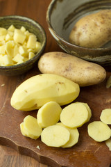 Naklejka na ściany i meble Potatoes and potato sliced on wooden table. Selective focus