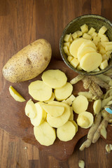Potatoes and potato sliced on wooden table. Selective focus