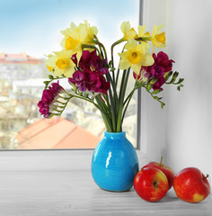 Vase with beautiful flowers on windowsill